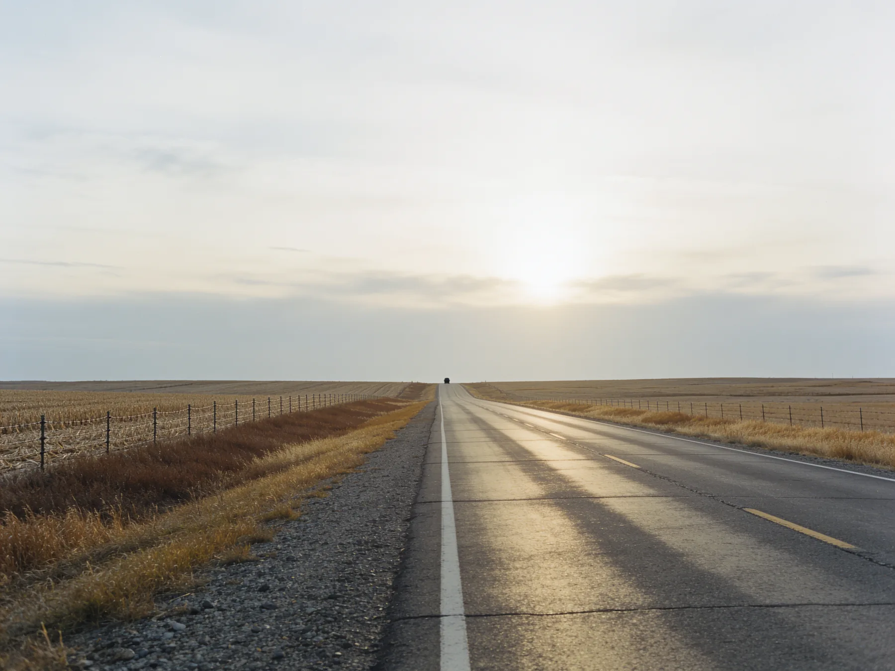 A prairie highway running to a flat horizon in late autumn