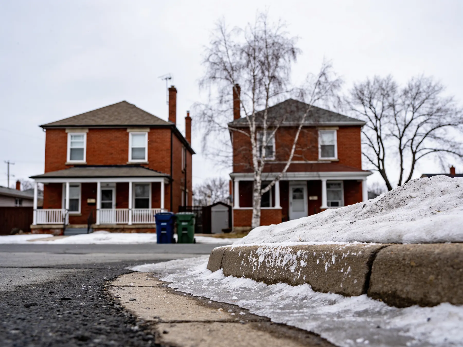 A residential street of semi-detached houses under grey February light