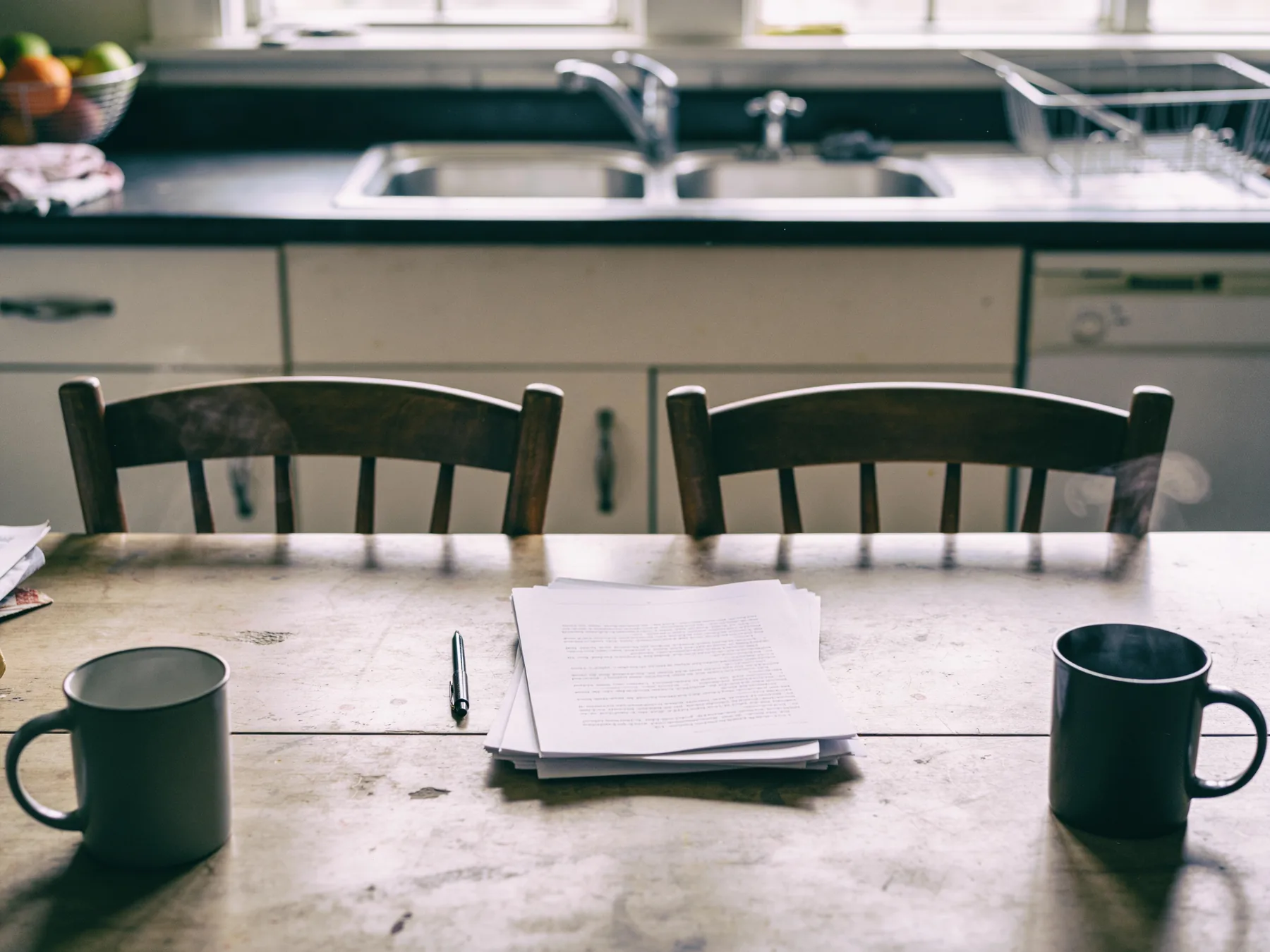 Two chairs at a kitchen table with paperwork between them