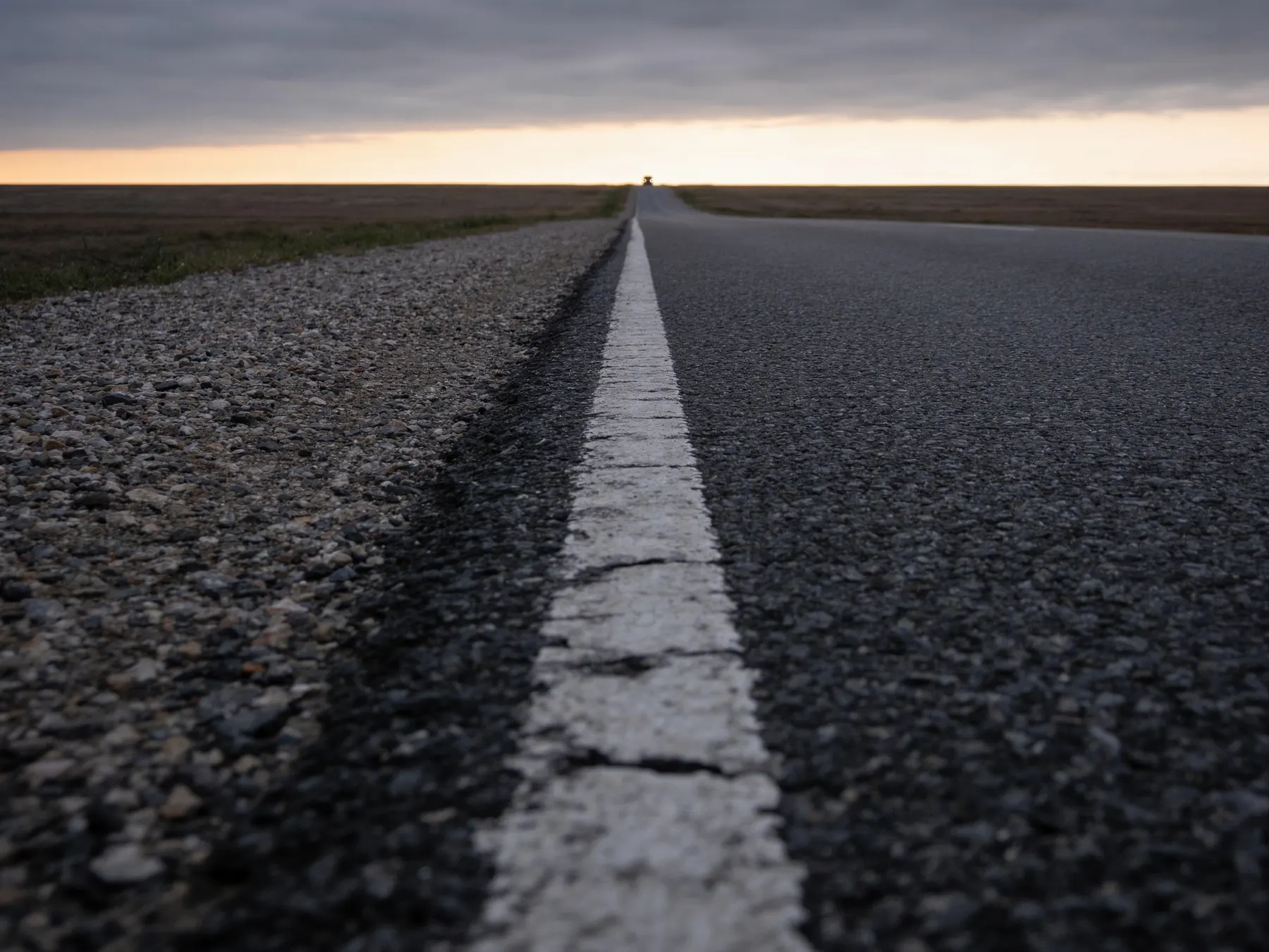 A long straight road disappearing toward a flat horizon