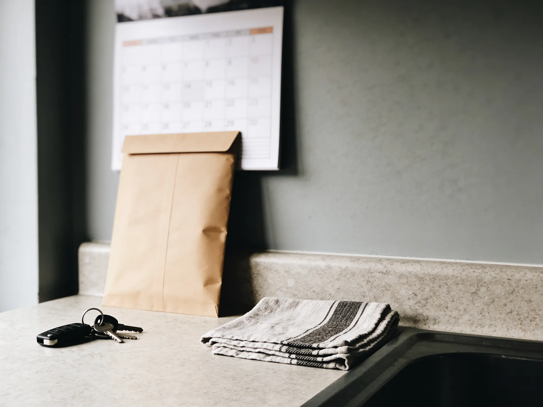 A brown envelope and a calendar on a kitchen counter in February