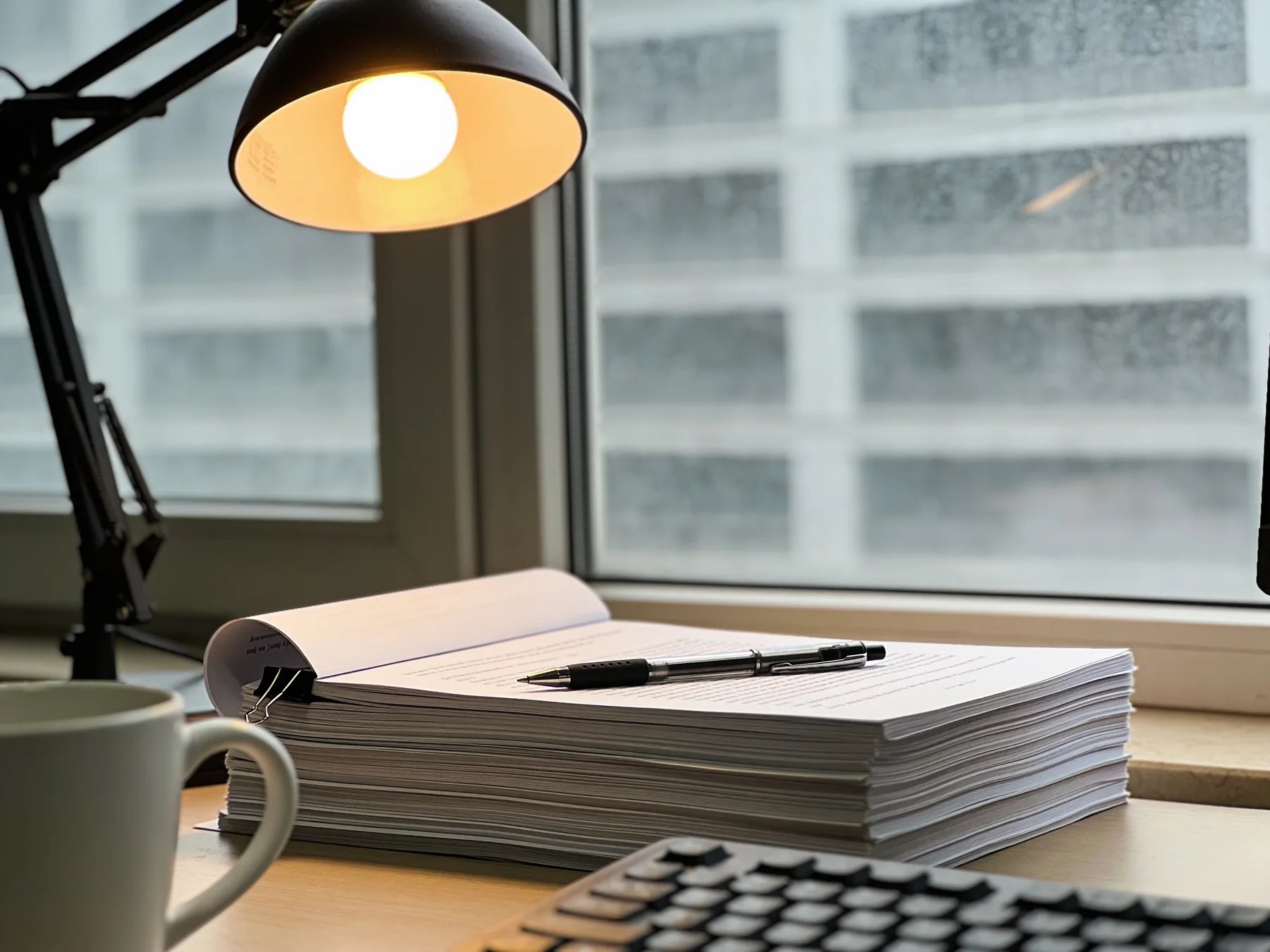 A desk with a printed application, a keyboard, and a coffee